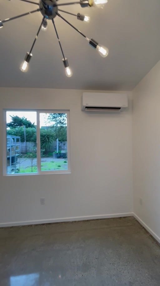 Bedroom with vaulted ceiling, window and polished concrete floor