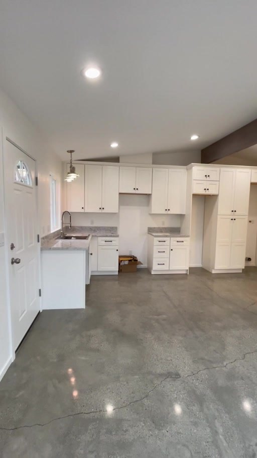 Vaulted kitchen with white birch cabinets and polished concrete floor