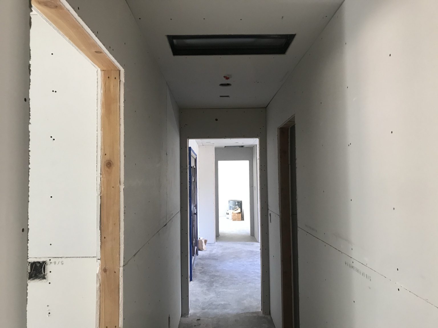 Hallway with new drywall and a skylight opening
