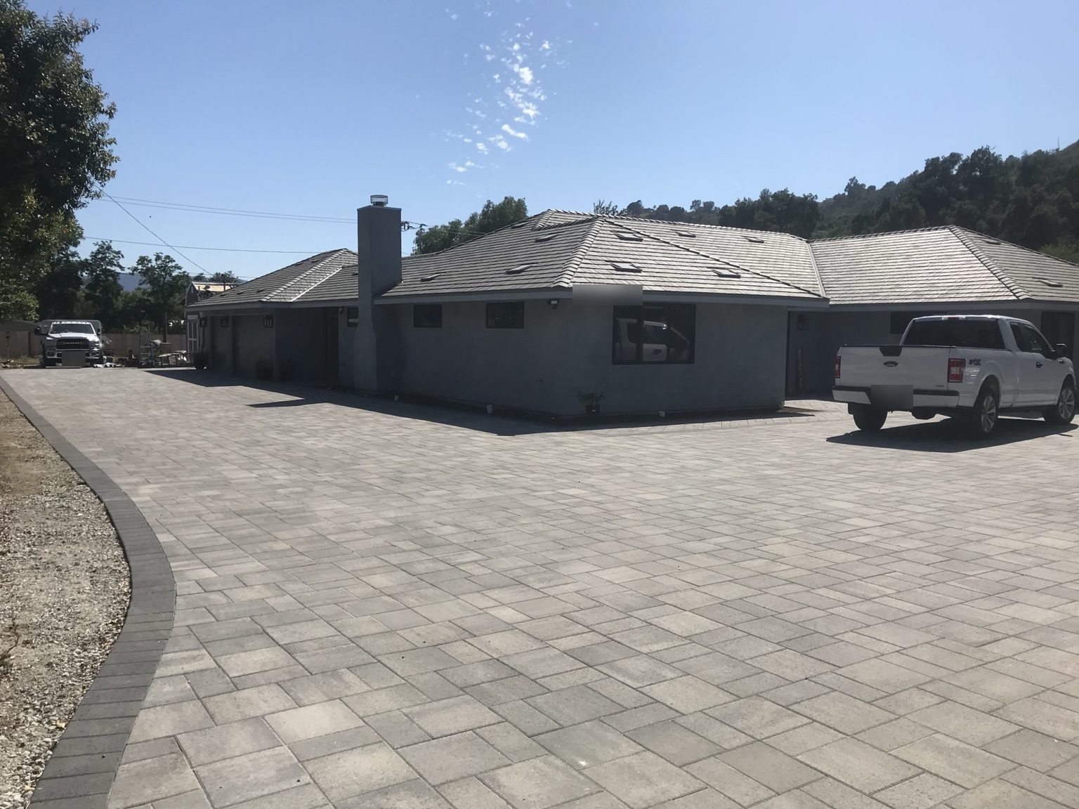 Completed single-story home with gray stucco, tile roof and a new paver driveway in Ojai