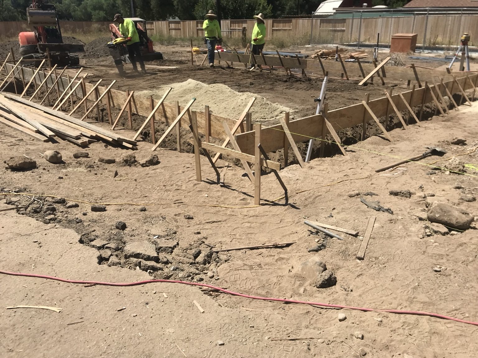 Foundation forms set while crew compacts the soil