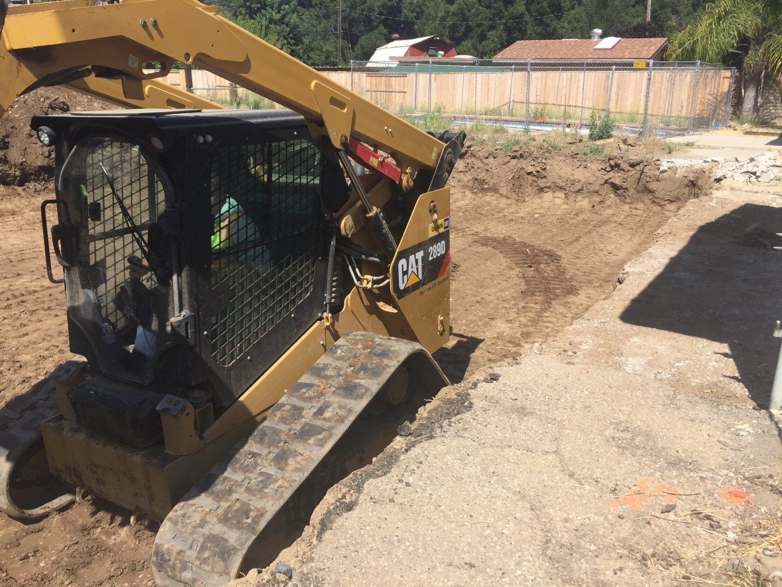 Track loader excavating beside existing concrete