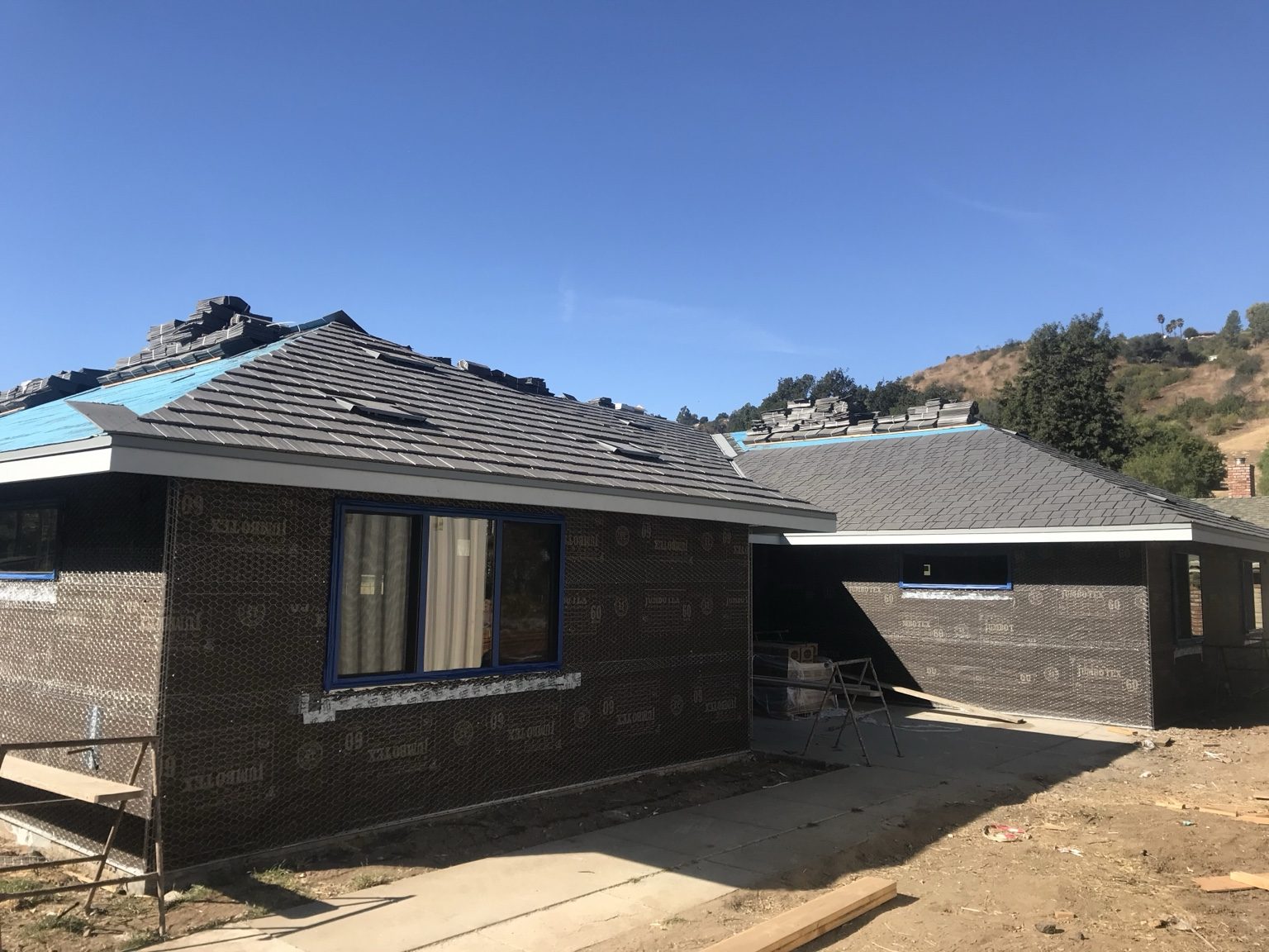 Stucco lath on the walls while roof tile is installed