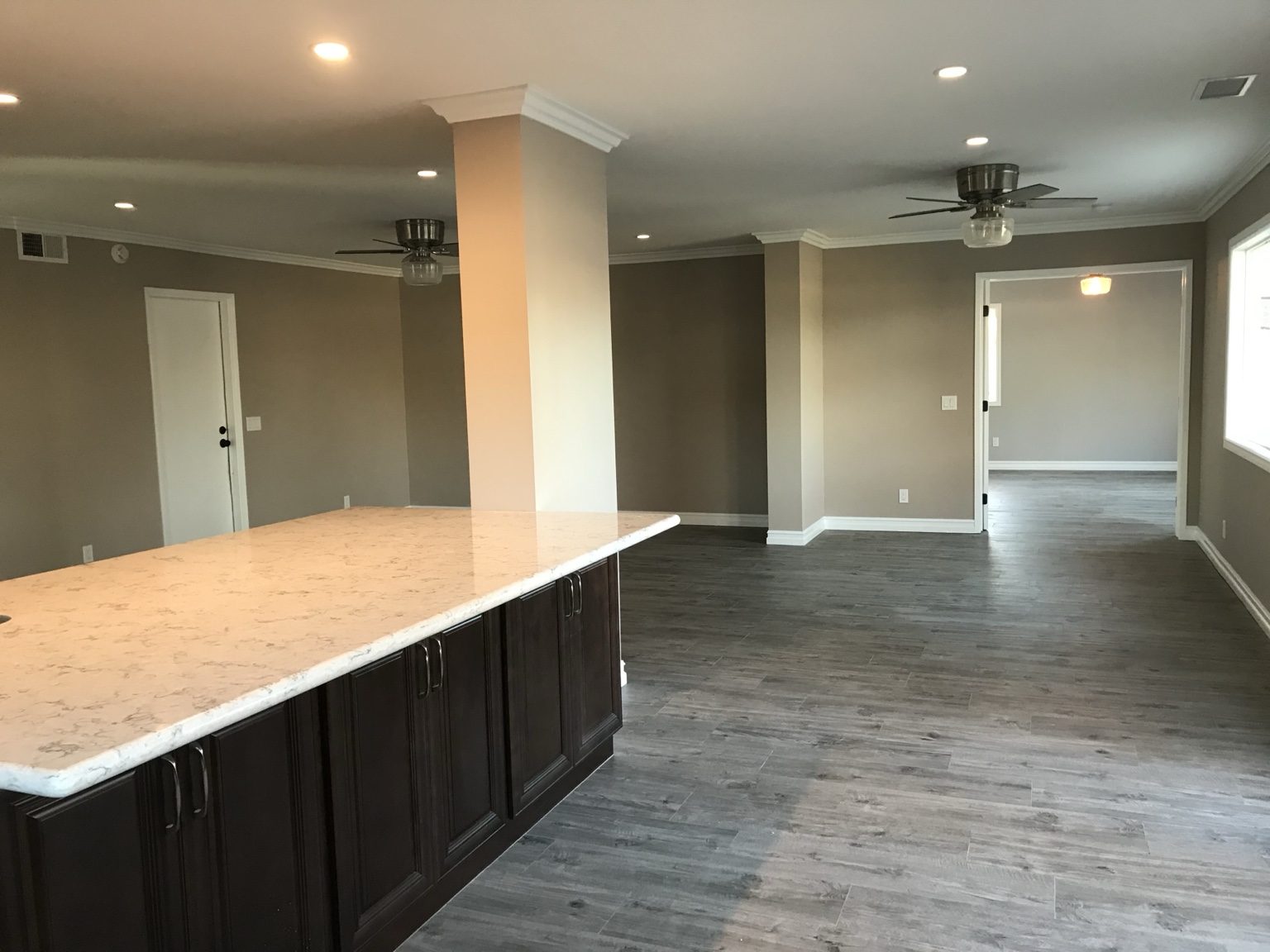 Open living area with crown molding and double doors into the primary bedroom