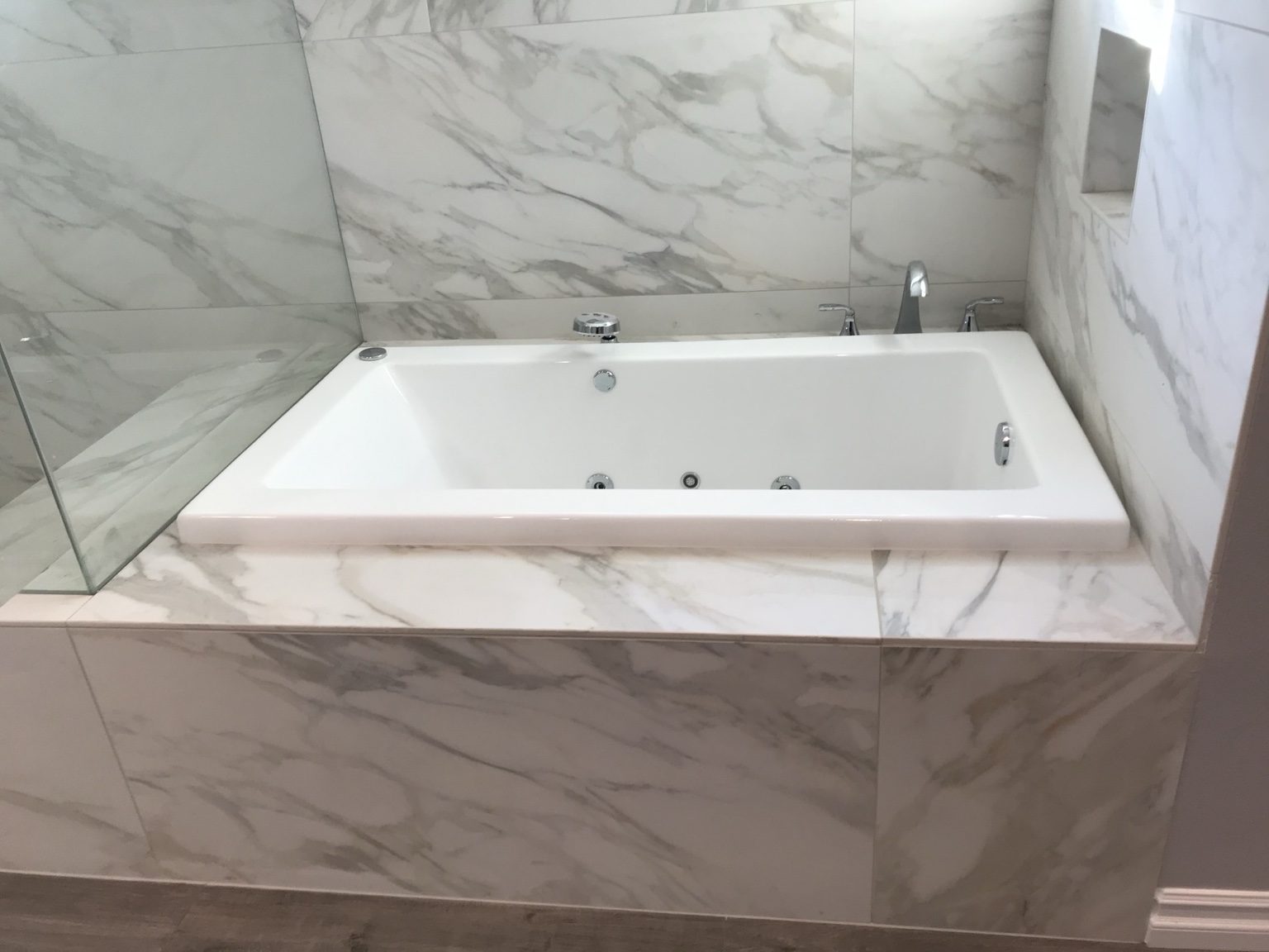 Jetted tub surrounded by large marble-look tile