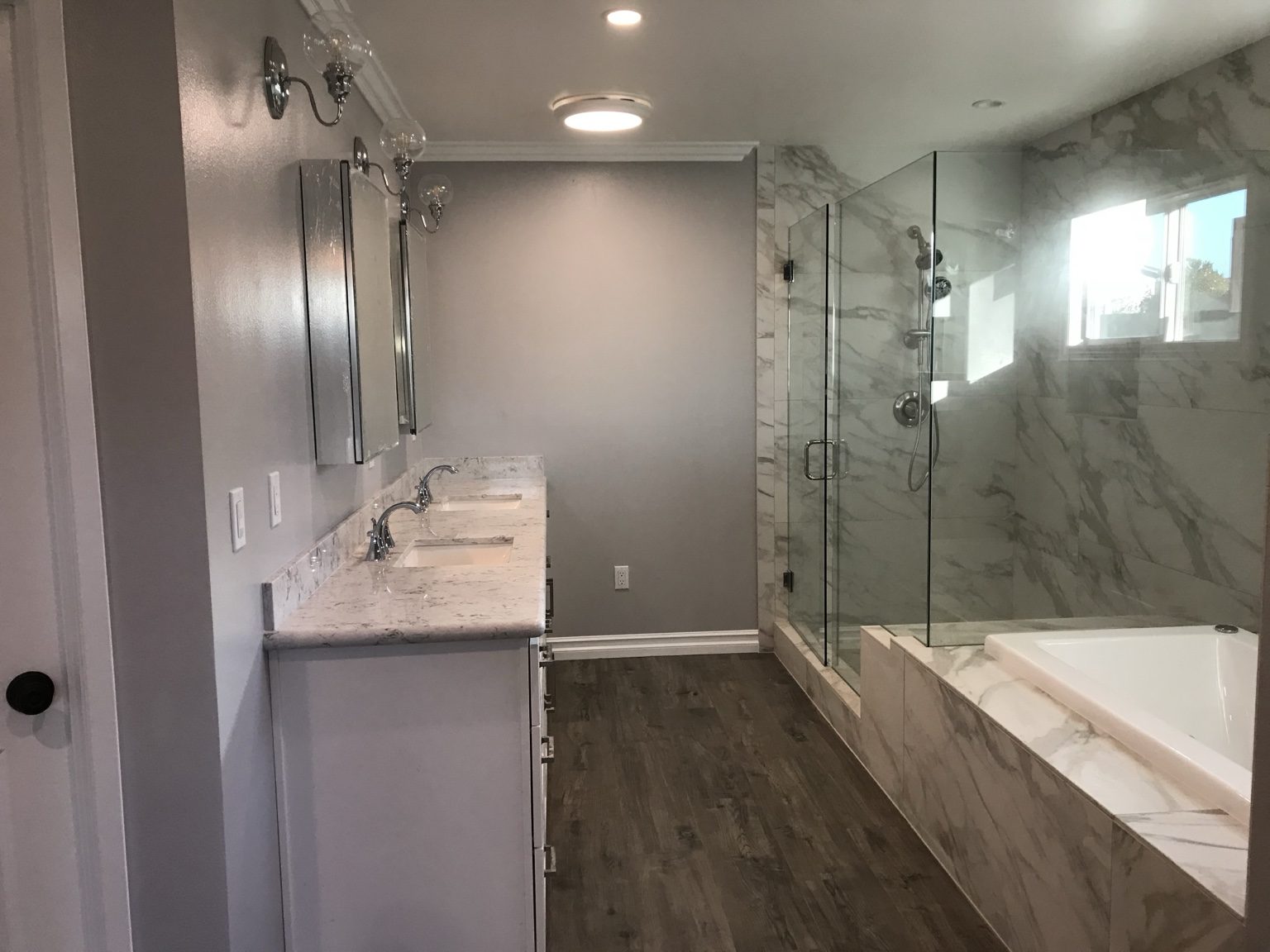 Primary bathroom with double vanity, glass shower and tiled tub