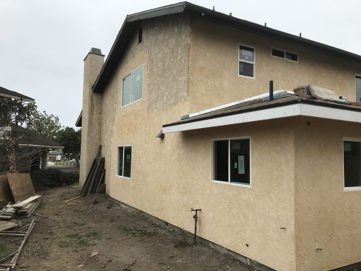 Finished stucco on the addition matching the existing two-story house