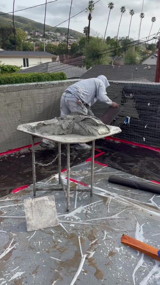 Plasterer applying stucco to the roof deck parapet walls