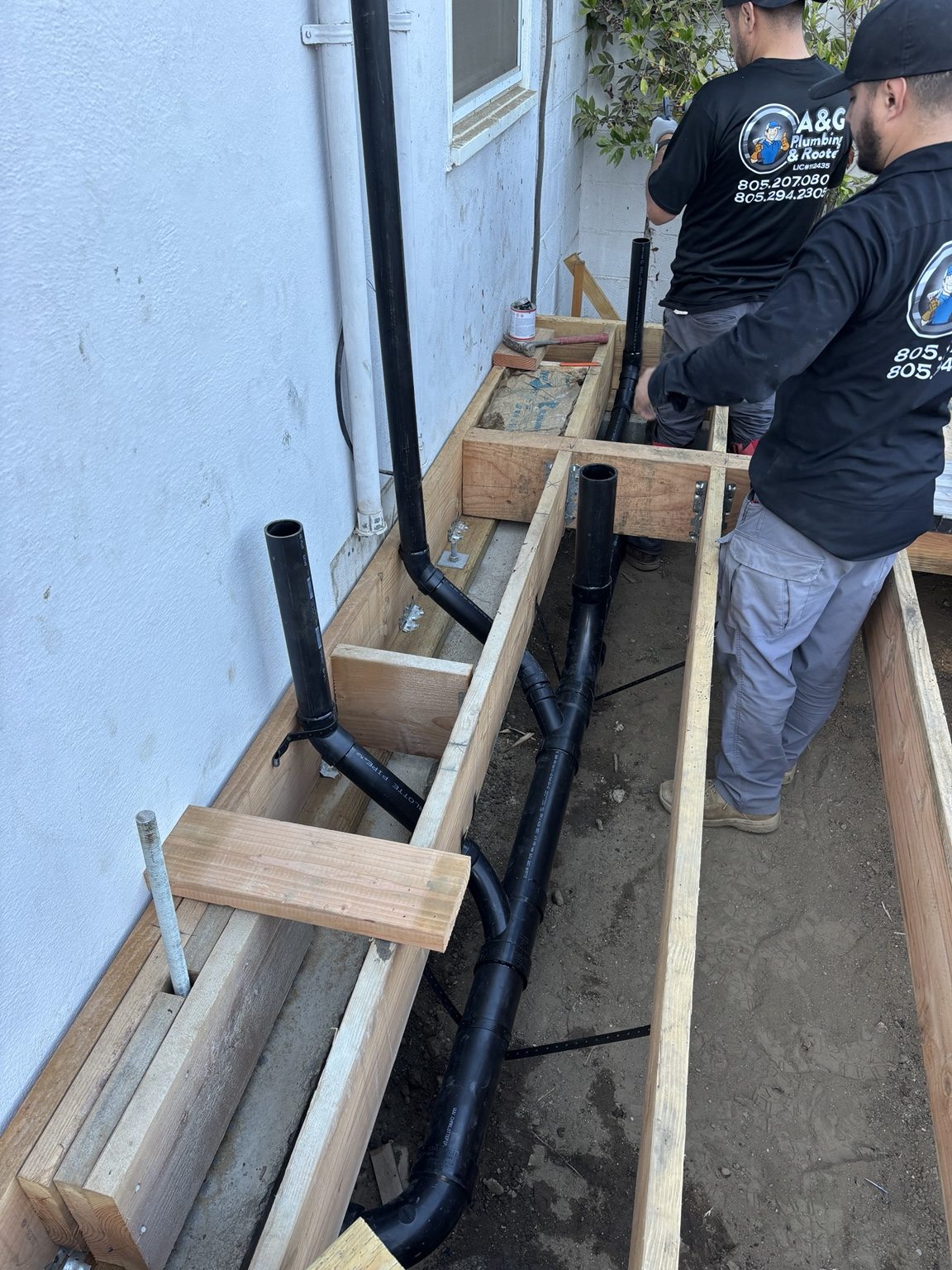 Plumbers installing drain lines under the raised floor