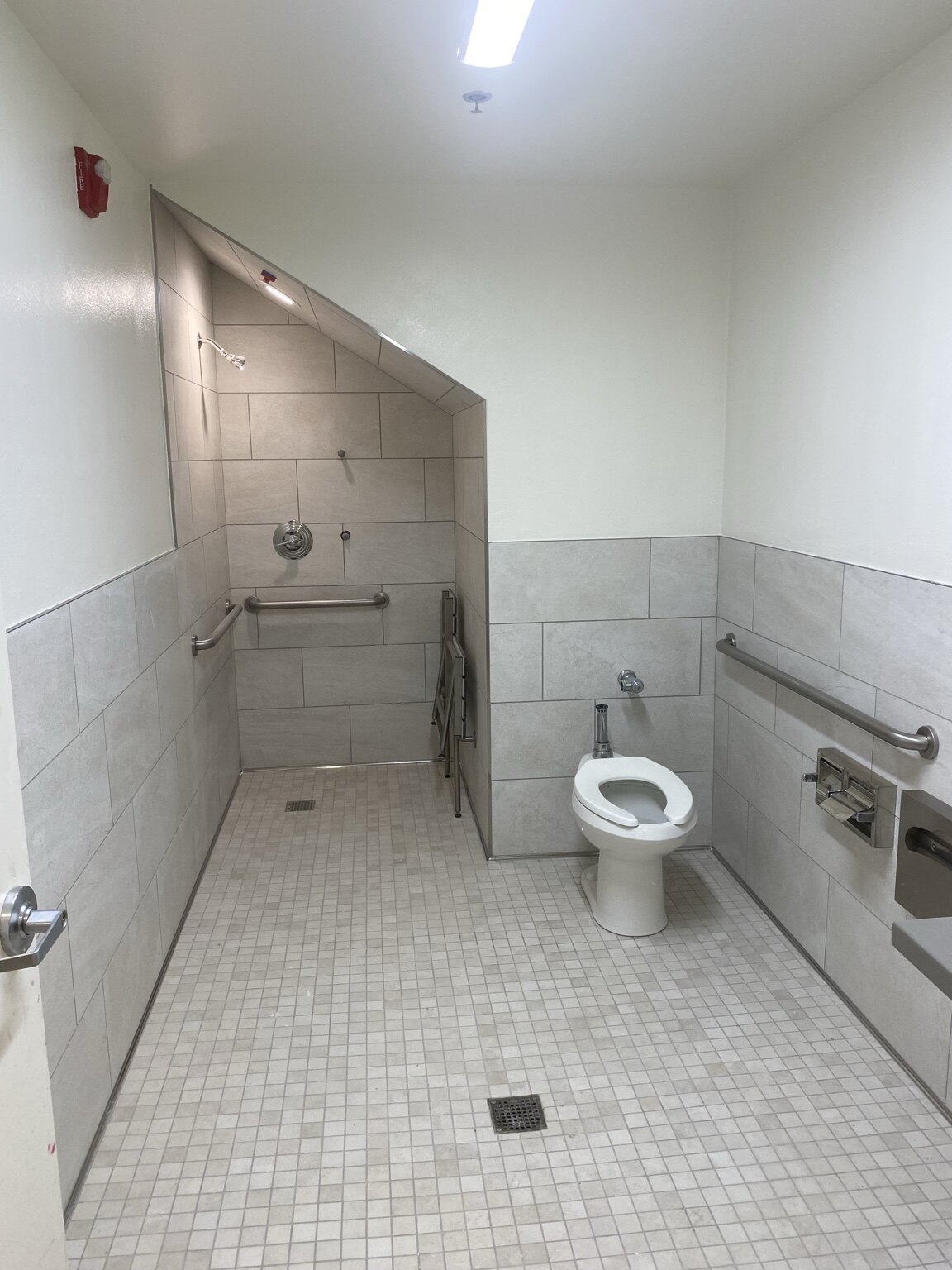 Completed accessible commercial restroom with grab bars and roll-in shower