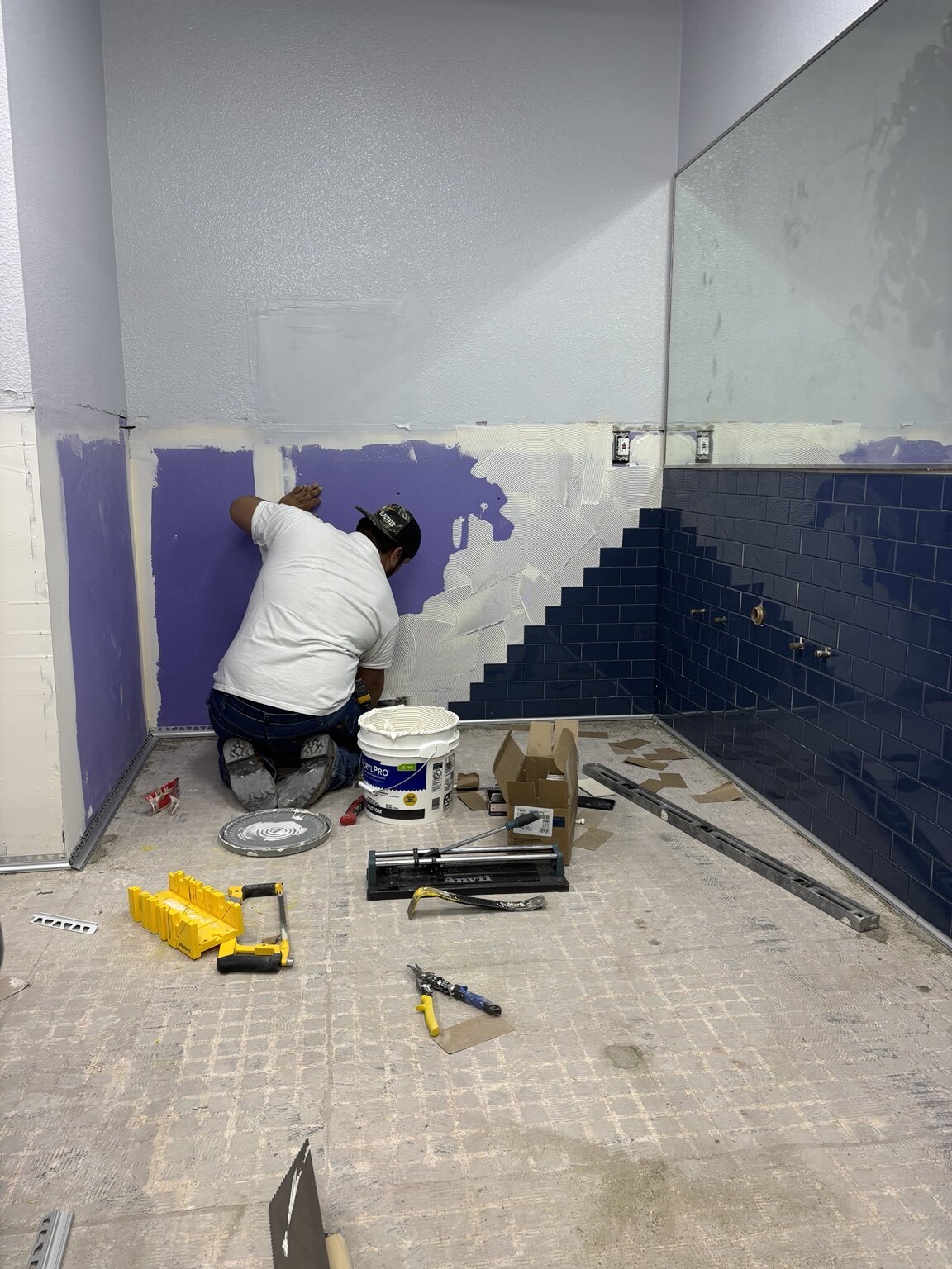 Blue wall tile being installed in a commercial restroom